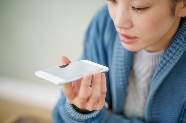 スマホに声を録音する女性